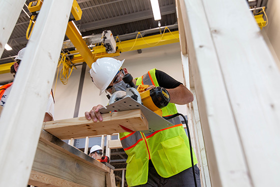 Student wearing hard hat and using power tools