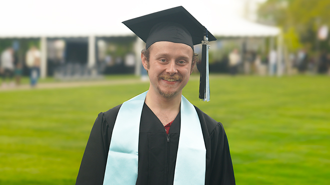 Thomas McDonough stands in his cap and gown at Commencement.