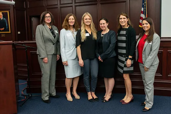 Women students, faculty, and alumni pose together at a conference