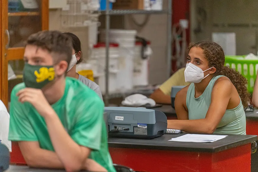 A student listening to Brian Wysor talk before doing a lab experiment.