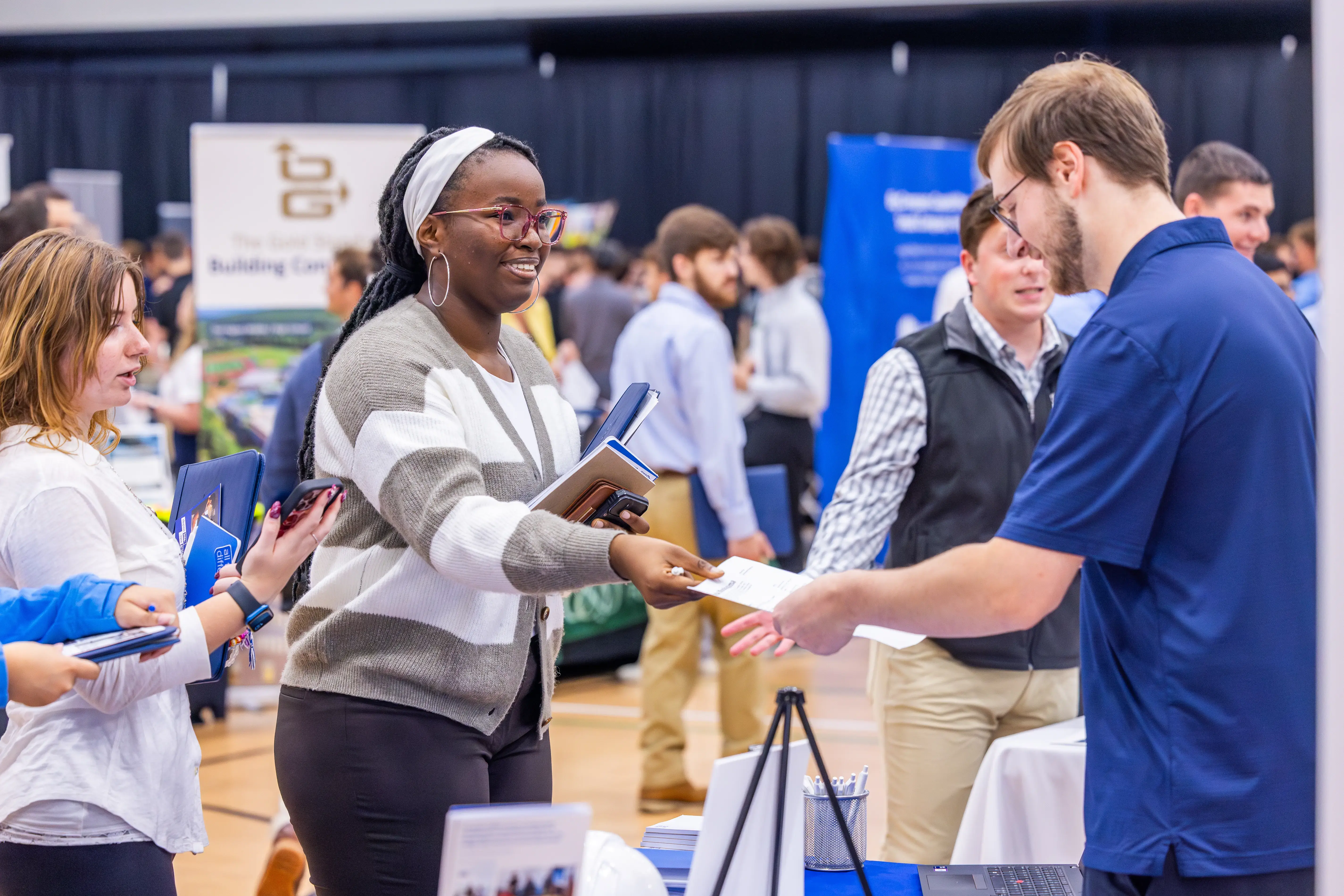 A student hands a potential employer a resume during a career fair