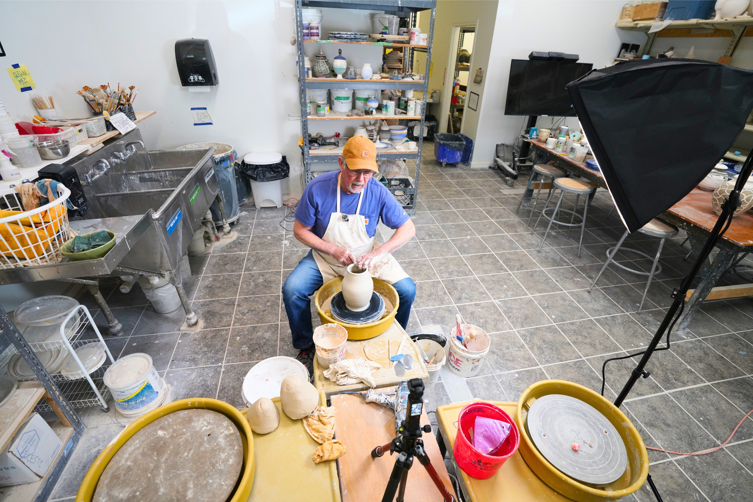 From above, Leonti works at the wheel while filming a ceramics lesson, shaping clay into a vessel for his growing online audience.