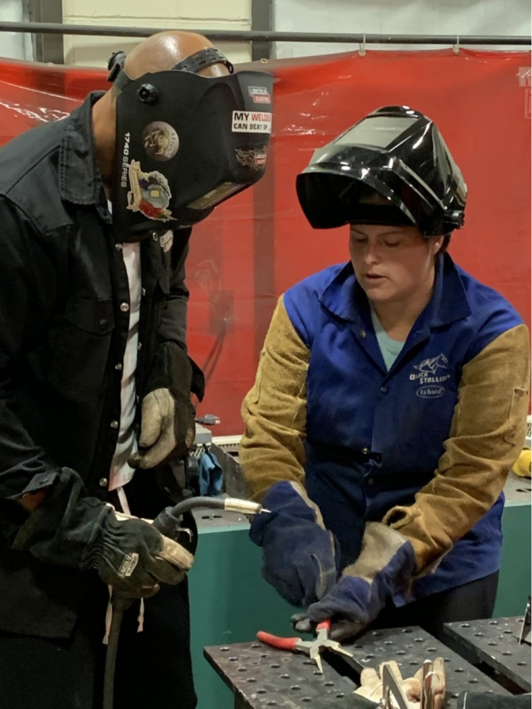 Instructor showing welding techniques to a student.