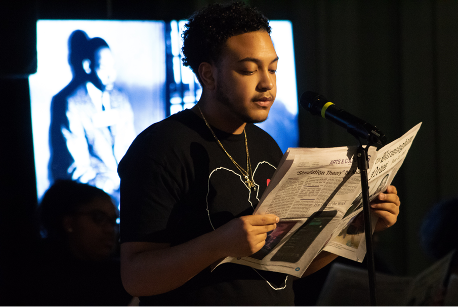 A student standing in front of a microphone during a Black History Month performance.
