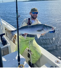 Malcolm Bowen in the bay holding a striped bass