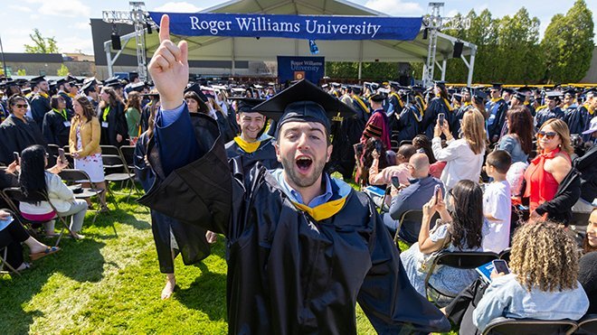 Graduate celebrates shouting and raising arm at commencement 2024