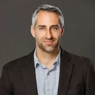 Sargon Donabed, portrait of a man with a blue collared shirt and black jacket.