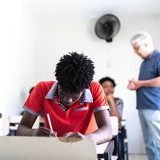 Students sit and take tests while a proctor observes