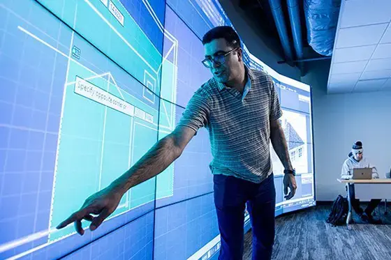 Teacher points at interactive wall of screens