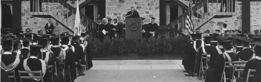 Historic photo of Roger Williams University’s Bristol campus showing faculty and students gathered outside a brick academic building, representing the university’s early history.