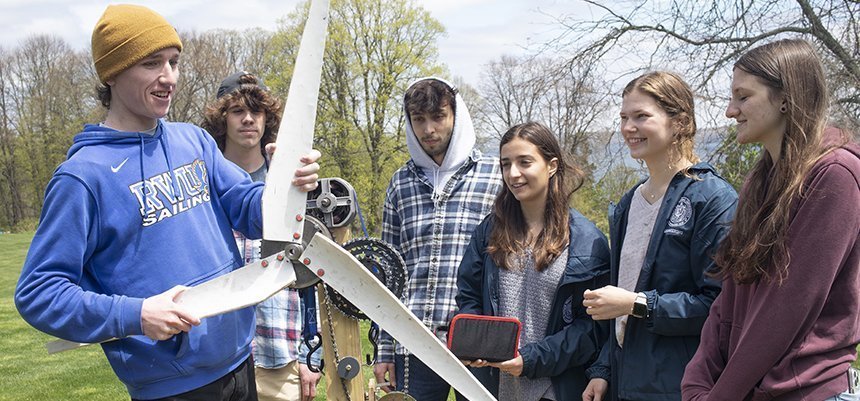 Students pose with a wind turbine that they built