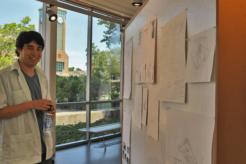 A student smiling by his pin-up work