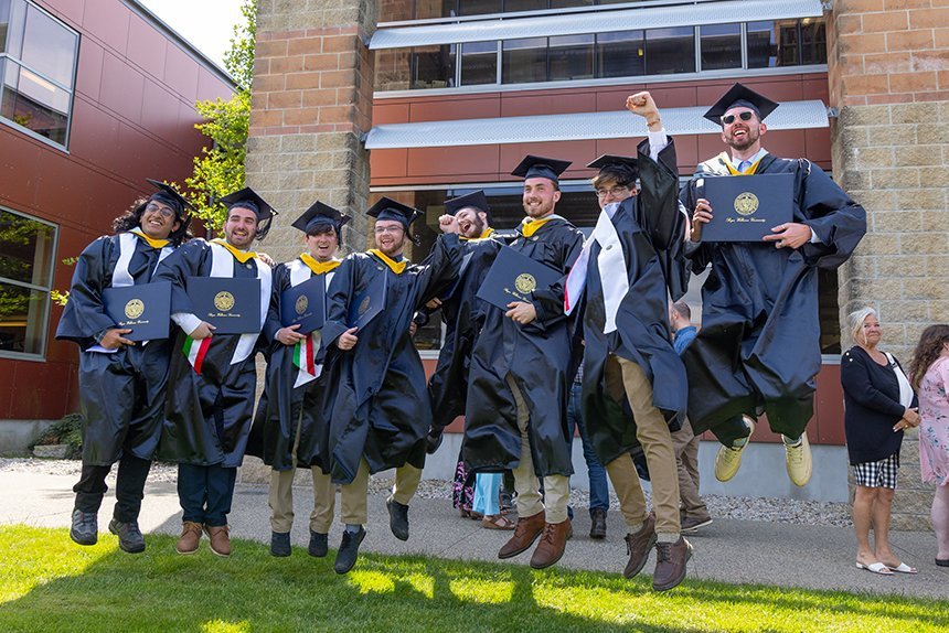 Graduates jump holding degrees