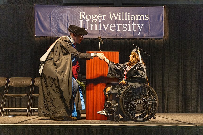 A graduate receives their degree on stage