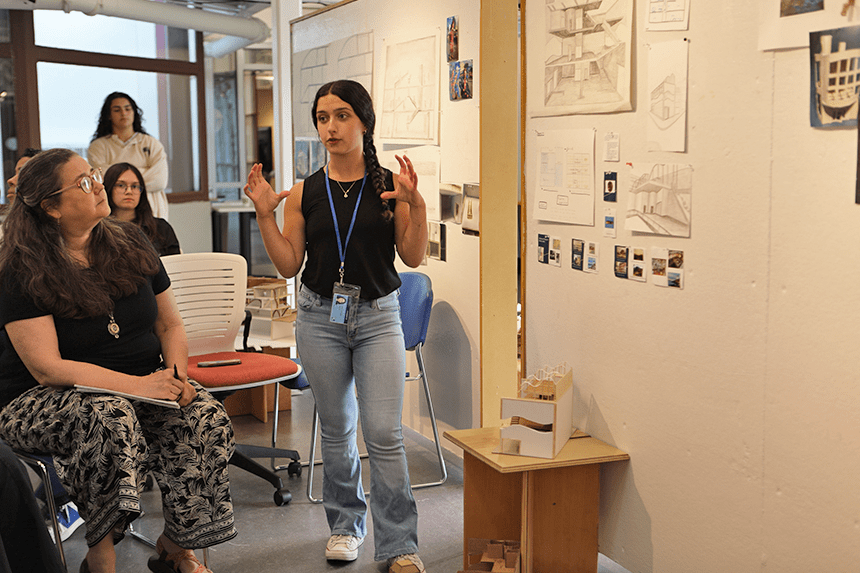 A student presenting their work displayed on a gallery wall