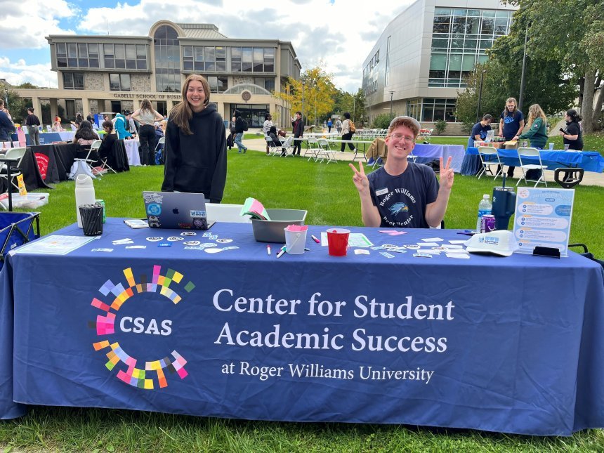 two peer mentors posing, smiling and putting up peace signs with their hands at the CSAS table at the wellness street fair