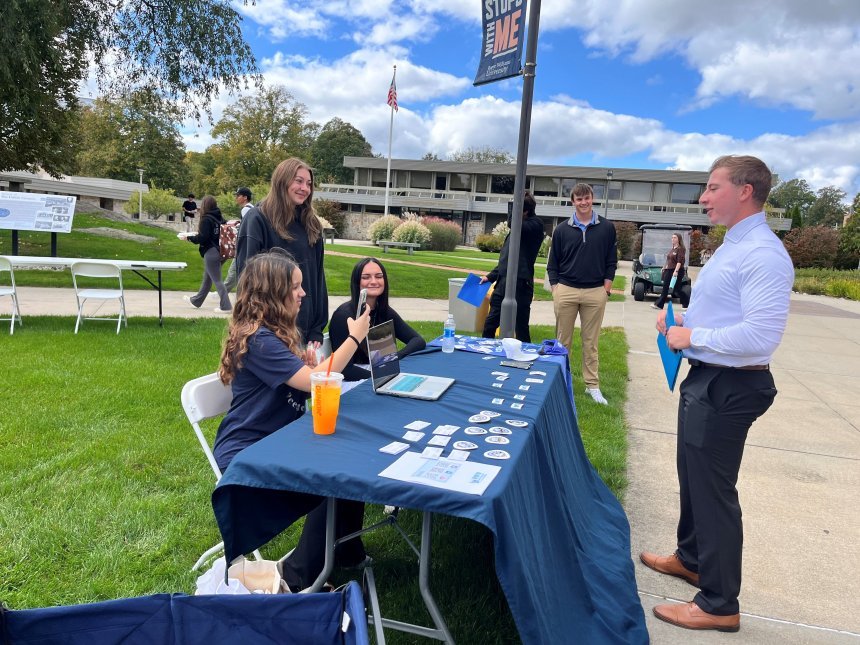 RWU community members interacting with three peer mentors behind one of our tables