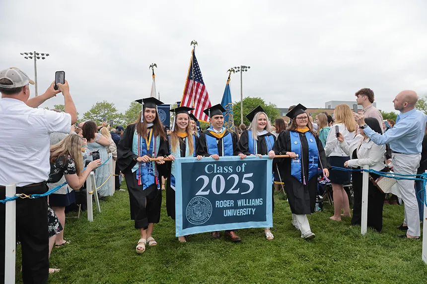 Graduates process with 2025 banner