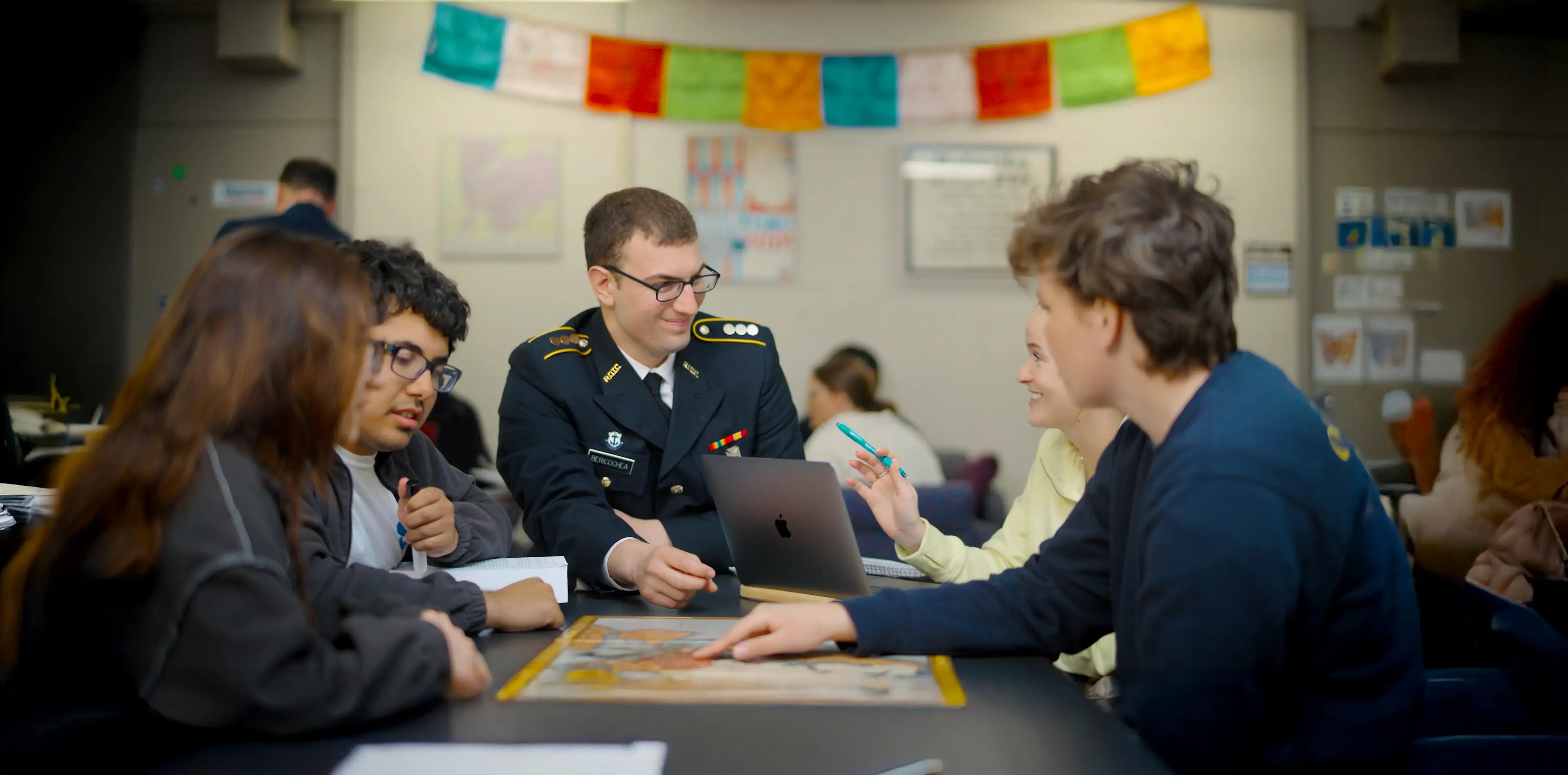 International relations students collaborate while discussing a map during a group project in a classroom setting.