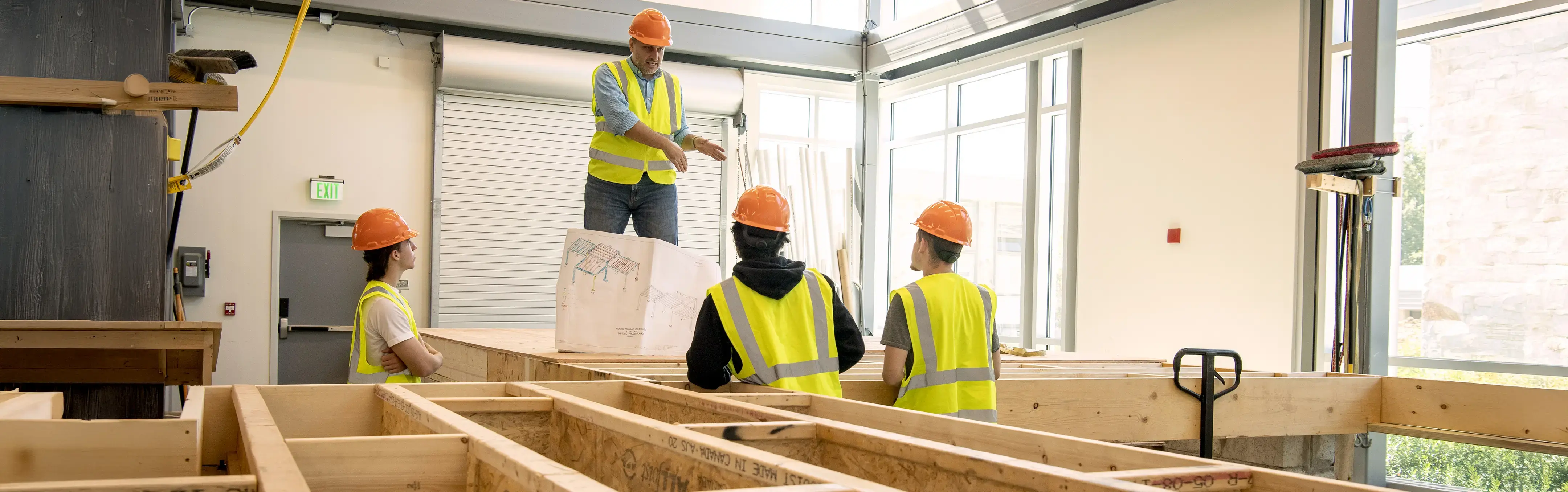 A carpentry professor works with EXT School students on a building project