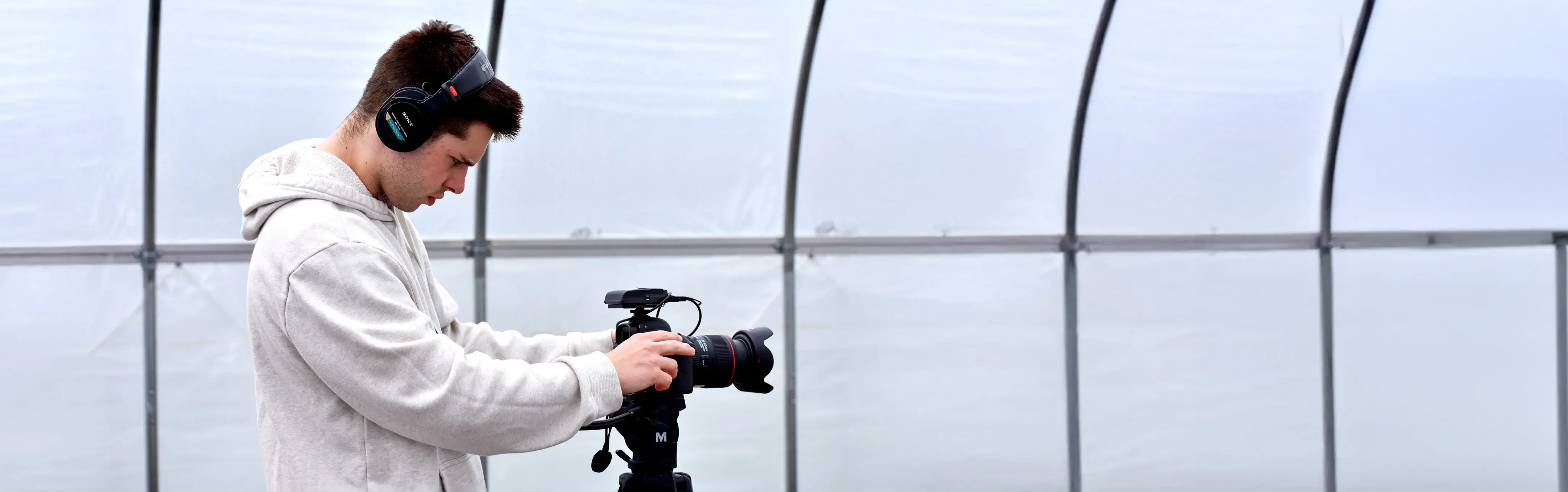 A videographer films a scene in a green house.