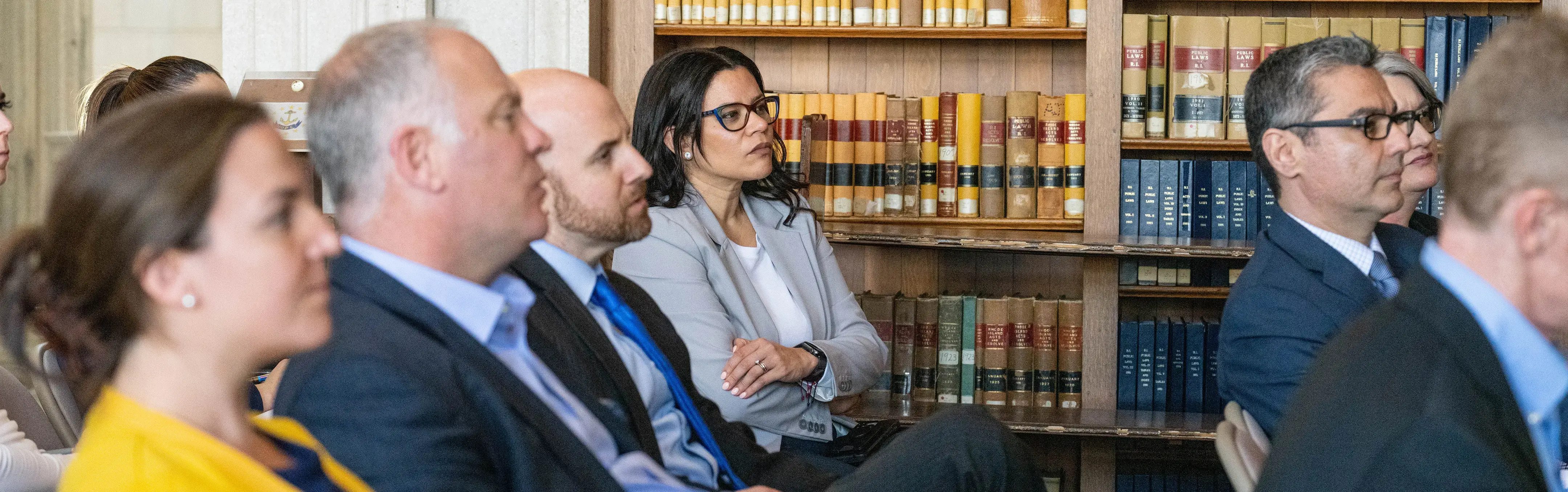 Professionally dressed individuals sit in room discussing policy