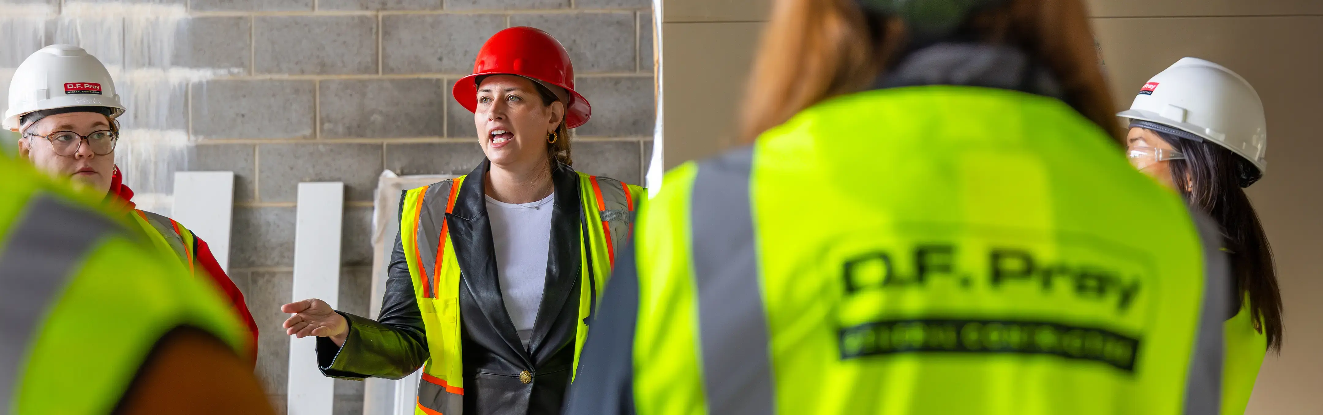 A construction company owner briefs a team in an active construction site