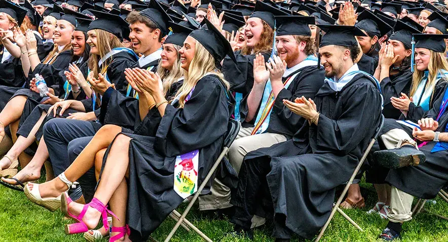Graduates sit and cheer at commencement
